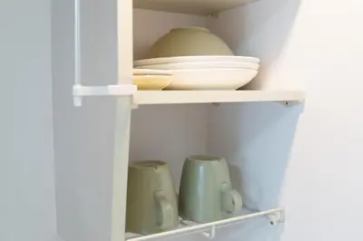 a cupboard with plates and bowls on a shelf at Ikebukuro Twin Room in Tokyo