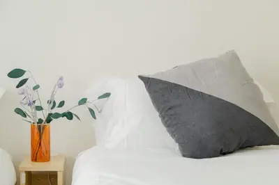 a pillow on a bed next to a vase with flowers at Ikebukuro 507 Twin Room in Tokyo