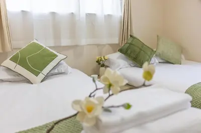 two beds in a hotel room with white and green pillows at Near skytree direct ueno asakusa,,baby bed,baby chair in Tokyo