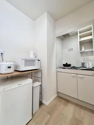 a small kitchen with white cabinets and a microwave at Ikeda Ueno 401 Quad room in Tokyo