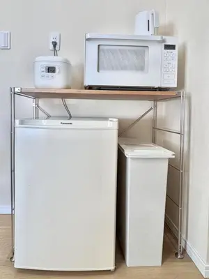 a microwave and a refrigerator under a table with a microwave at Ikeda Ueno 401 Quad room in Tokyo