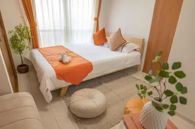 a small bedroom with a bed with an orange blanket at \u697d\u697d\u6c11\u6cca in Tokyo