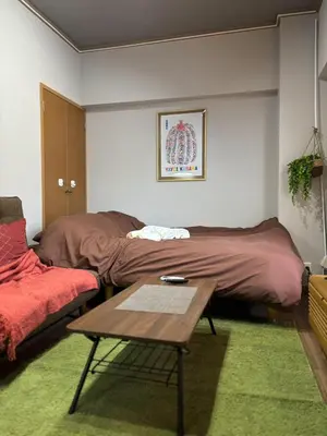 a living room with a bed and a table at \u9ad8\u7530\u99ac\u5834\u99c55\u5206 \u65b0\u5bbf10\u5206 \u30ab\u30d5\u30a7\u3068\u30a2\u30fc\u30c8\u306e\u30ea\u30e9\u30c3\u30af\u30b9\u7a7a\u95931R good in Tokyo