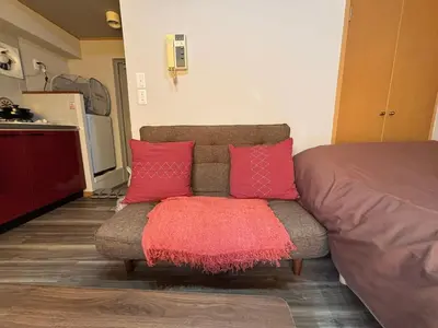 a couch with two red pillows in a room at \u9ad8\u7530\u99ac\u5834\u99c55\u5206 \u65b0\u5bbf10\u5206 \u30ab\u30d5\u30a7\u3068\u30a2\u30fc\u30c8\u306e\u30ea\u30e9\u30c3\u30af\u30b9\u7a7a\u95931R good in Tokyo