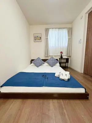 a bedroom with a large bed with a blue blanket at \u685c\u306e\u5ddd67 \u6e0b\u8c37\u533a\u4e28\u65b0\u5bbf\u307e\u3067\u4e00\u99c5 2-10\u4eba\u4e28Shibuya One stop to Shinjuku 2-10 people in Tokyo