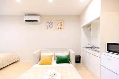a small bedroom with a bed with yellow and green pillows at Mi-HOTEL UENO in Tokyo