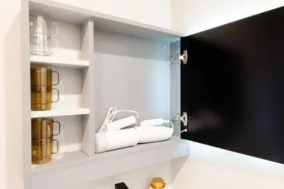 a bathroom with white shelves with cups and towels at Mi-HOTEL UENO in Tokyo