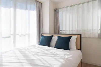 a bed with blue pillows in front of a window at DeLCCS\u8981\u753a in Tokyo