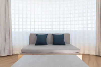 a couch with two blue pillows in front of a window at DeLCCS\u8981\u753a in Tokyo