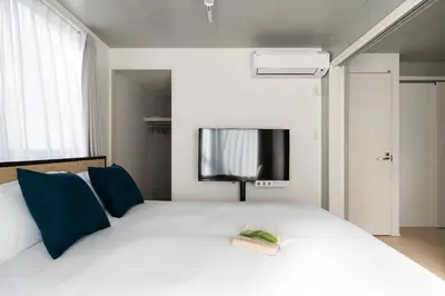 a bedroom with a bed with a tv on the wall at Bel Avenir in Tokyo