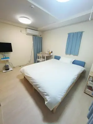 a bedroom with a large white bed and blue curtains at ToyamaHouse2-203 in Tokyo