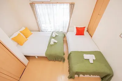 two beds in a small room with green and red pillows at Mori house\u738b\u5b50\u672c\u753a in Tokyo