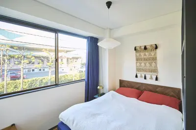 a bedroom with a red bed and a large window at HOTEL HONjoy in Tokyo