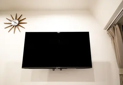 a flat screen tv hanging on a wall with a clock at \u9280\u5ea7\u7dda\u3059\u3050\u8fd1\u304f \u6b74\u53f2\u5bfa\u9662\u5de1\u308a\u306b\u6700\u9069 \u677e\u304c\u8c37\u306e\u9759\u304b\u306a\u4e00\u8ed2\u5bb6 Sio1g in Tokyo