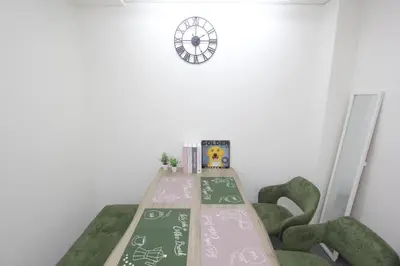 a table with green chairs and a clock on a wall at LUANA in SHIN-KOUENJI in Tokyo