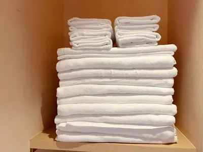 a stack of white towels on a shelf at hananosato \u9ad8\u7530\u99ac\u5834 in Tokyo