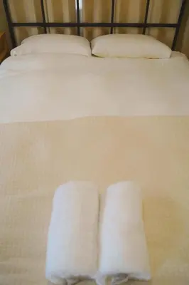two towels are sitting on a white bed at \u30cd\u30ae\u30cf\u30a6\u30b9,Negi House with Retro Vibes in Shopping Street,Group Friendly in Tokyo