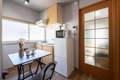 a small kitchen with a table and a refrigerator at Sumida Skytree hostel in Tokyo