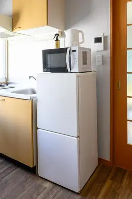 a microwave on top of a refrigerator in a kitchen at Sumida Skytree hostel in Tokyo