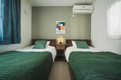 two beds in a small room with green sheets at Ikebukuro Urban Retreat in Tokyo