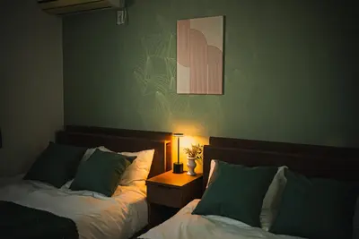 a bedroom with two beds and a table with a lamp at Ikebukuro Urban Retreat in Tokyo