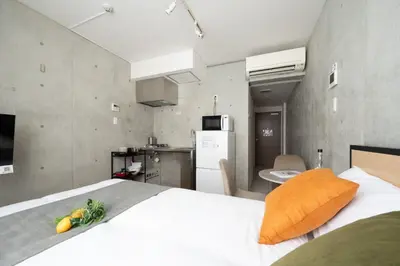 a bedroom with a white bed and a kitchen at Exam\u9ad8\u7530\u99ac\u5834 in Tokyo