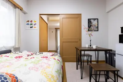 a bedroom with a bed and a table and a kitchen at SHIBUYA Bright Modern 40sqm Apartment FAMILY FRIENDLY!! in Tokyo