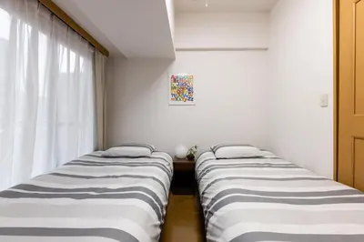 two beds in a room with a window at SHIBUYA Bright Modern 40sqm Apartment FAMILY FRIENDLY!! in Tokyo