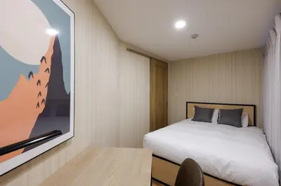 a bedroom with a bed and a painting on the wall at \u30b3\u30eb\u30c6\u30a3\u30fc\u30ec\u56db\u8c37\u672c\u5869\u753a in Tokyo