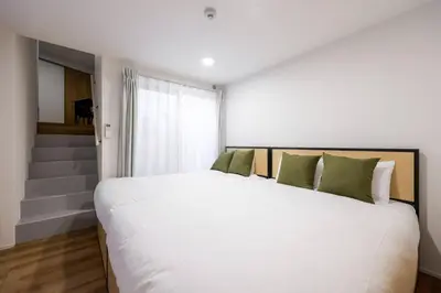 a bedroom with a large white bed with green pillows at \u30b3\u30eb\u30c6\u30a3\u30fc\u30ec\u56db\u8c37\u672c\u5869\u753a in Tokyo