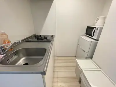 a small kitchen with a sink and a microwave at Comma House Nishi-Ikebukuro 3F in Tokyo