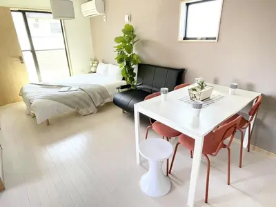 a living room with a bed and a table and chairs at Comma House Kitaikebukuro 301 in Tokyo
