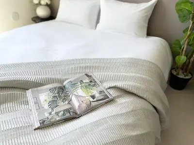 a book on a bed with a white bedspread at Comma House Kitaikebukuro 301 in Tokyo