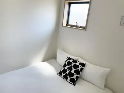 a white couch with a black and white pillow on it at Comma House Kitaikebukuro 301 in Tokyo