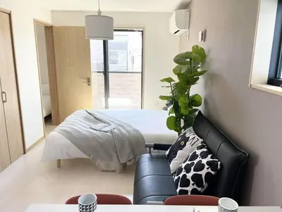 a bedroom with a bed and a couch and a chair at Comma House Kitaikebukuro 301 in Tokyo