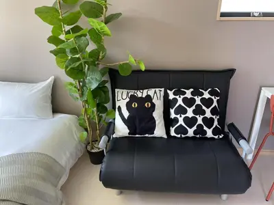 a black chair in a bedroom with a black cat pillow at Comma House Kitaikebukuro 301 in Tokyo