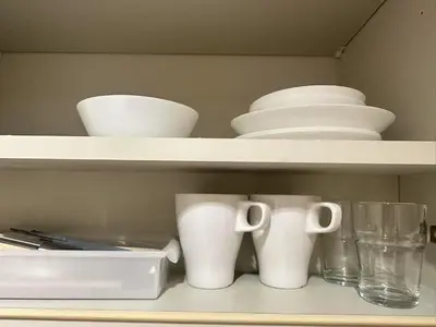 a shelf with white dishes and cups on it at Shibuya\u306e\u5bbf in Tokyo
