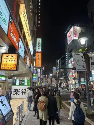 a crowd of people walking down a busy city street at night at Shibuya\u306e\u5bbf in Tokyo