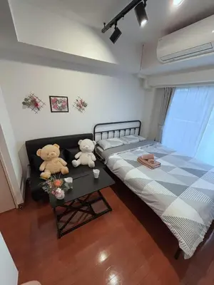 two teddy bears sitting on a bed in a bedroom at Shibuya\u306e\u5bbf in Tokyo
