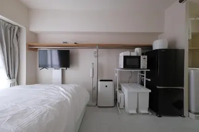 a bedroom with a bed and a microwave and a tv at 5min walk to Kameari Station within 30min to Ginza, Asakusa, Skytree Direct bus to Haneda Airport & Tokyo Disneyland departing from Kameari Station in Tokyo