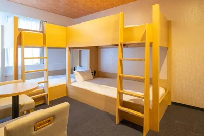 a dorm room with bunk beds with a table and a tablektop at Tosei Hotel Cocone Kamata in Tokyo