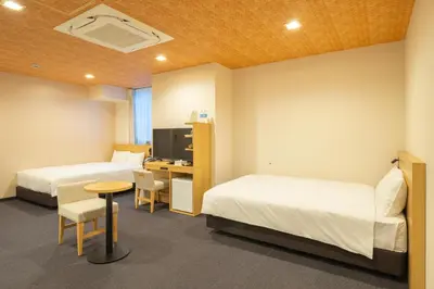 a hotel room with two beds and a desk and a tv at Tosei Hotel Cocone Kamata in Tokyo