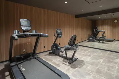 a gym with treadmills and ellipticals in a room at Tosei Hotel Cocone Kamata in Tokyo