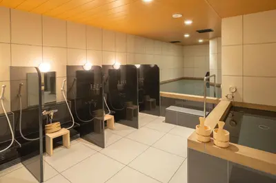 a bathroom with several urinals and a bath tub at Tosei Hotel Cocone Kamata in Tokyo