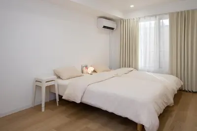 a white bedroom with a bed and a stool at M House Tokyo Omori\u99c5 in Tokyo