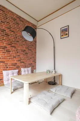 a room with a wooden table and a brick wall at Minowa Sta Direct to Ueno in Tokyo