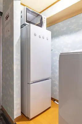 a refrigerator with a microwave on top of it at Minowa Sta Direct to Ueno in Tokyo