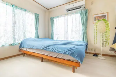 a bedroom with a bed with blue sheets and windows at Minowa Sta Direct to Ueno in Tokyo