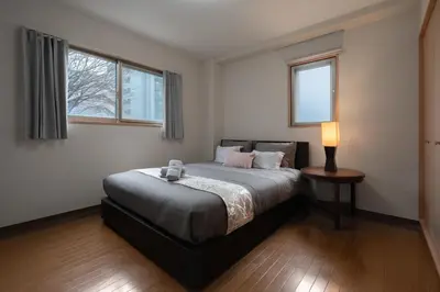 a bedroom with a bed with a lamp and two windows at Mita Hillside Villa 4BR 3Bathrooms in Tokyo