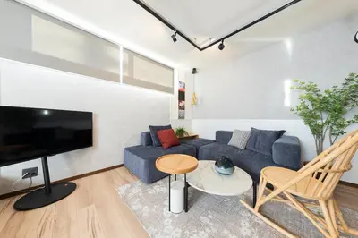 a living room with a blue couch and a tv at \u3077\u3075\u304b\u30b7\u30bf\u30e4\u516b\u5e83 in Tokyo